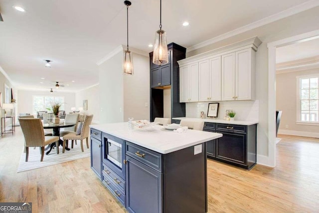 kitchen featuring white cabinetry, light hardwood / wood-style flooring, stainless steel microwave, and a kitchen island