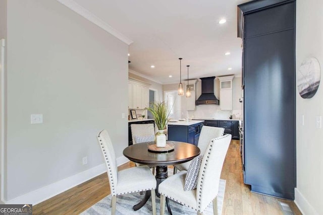 dining room with light hardwood / wood-style floors and crown molding