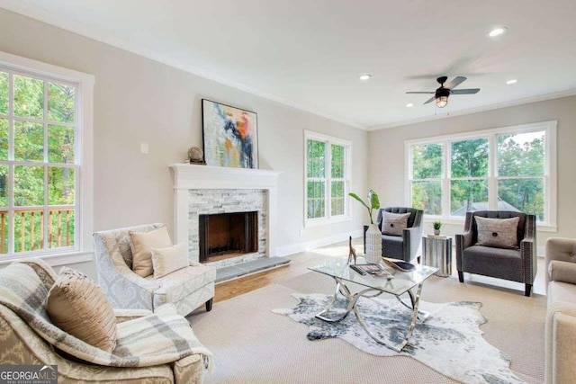 living room featuring crown molding, plenty of natural light, a fireplace, and ceiling fan