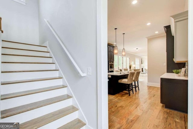 staircase featuring crown molding and hardwood / wood-style flooring