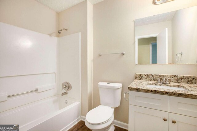 full bathroom with toilet, wood-type flooring, vanity, washtub / shower combination, and a textured ceiling