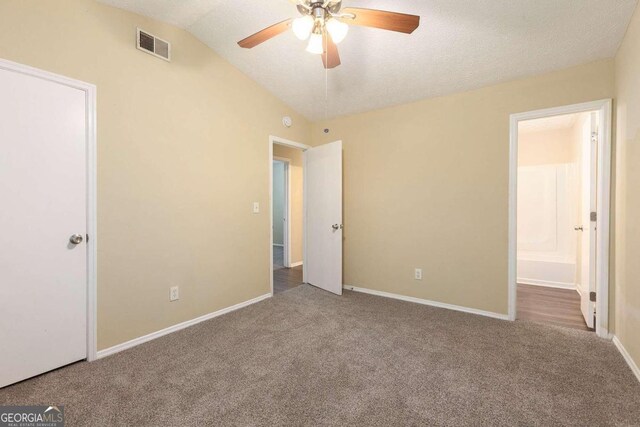 unfurnished bedroom with carpet, vaulted ceiling, a textured ceiling, ensuite bathroom, and ceiling fan