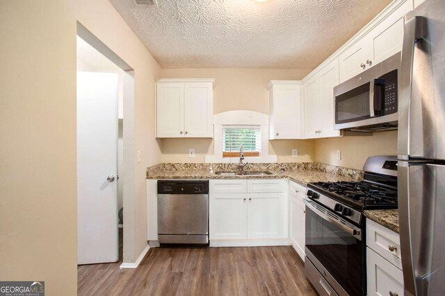 kitchen with white cabinetry, a textured ceiling, appliances with stainless steel finishes, and sink