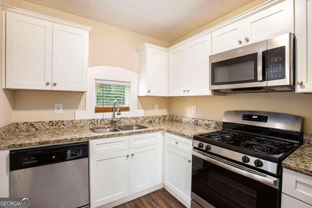 kitchen featuring stainless steel appliances, a textured ceiling, sink, and white cabinets