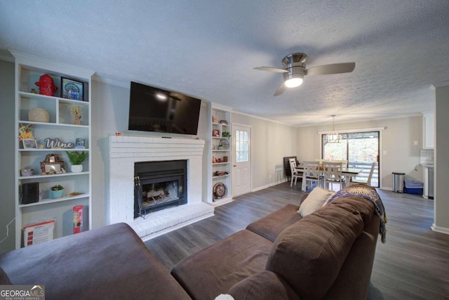 living room featuring ceiling fan, dark hardwood / wood-style flooring, crown molding, and a brick fireplace