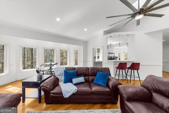 living area with baseboards, light wood-style flooring, recessed lighting, ceiling fan, and vaulted ceiling