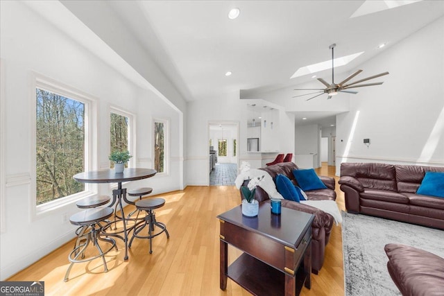 living room featuring high vaulted ceiling, a ceiling fan, recessed lighting, light wood-style floors, and a skylight