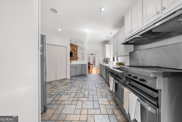 kitchen with stone tile floors, recessed lighting, ventilation hood, and freestanding refrigerator