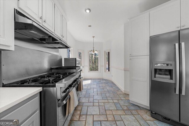 kitchen featuring stone tile floors, exhaust hood, white cabinetry, and appliances with stainless steel finishes