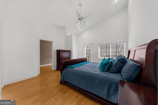 bedroom with a ceiling fan, light wood-style floors, baseboards, and high vaulted ceiling