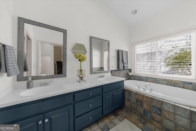 bathroom featuring double vanity, a bath, vaulted ceiling, and a sink