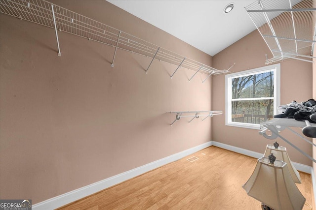 walk in closet featuring visible vents, light wood-style floors, and vaulted ceiling