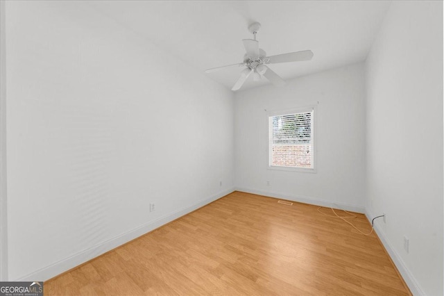 empty room with light wood-style flooring, a ceiling fan, and baseboards