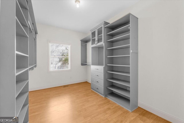 walk in closet with light wood-style flooring