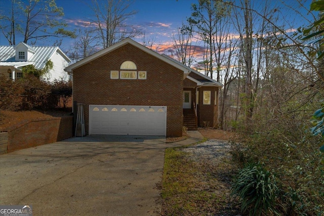 view of side of property with concrete driveway, an attached garage, and brick siding