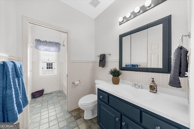 bathroom featuring visible vents, toilet, wainscoting, bathtub / shower combination, and vanity