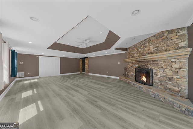 unfurnished living room with wood finished floors, baseboards, a fireplace, ceiling fan, and a raised ceiling