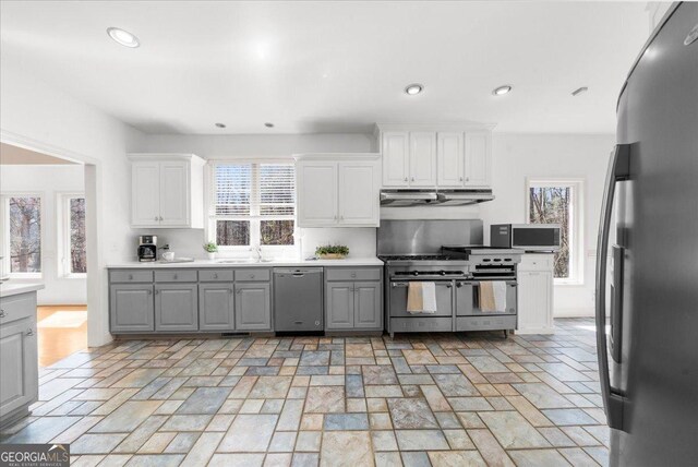 kitchen featuring gray cabinetry, under cabinet range hood, white cabinets, stainless steel appliances, and a sink