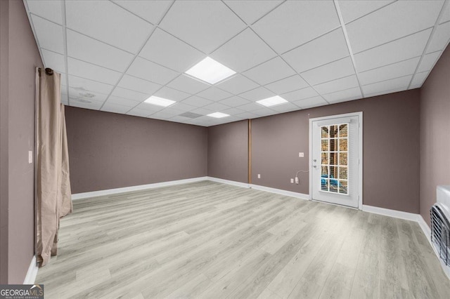 spare room featuring a paneled ceiling, baseboards, and wood finished floors