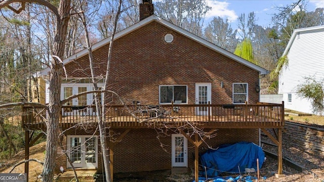 rear view of property featuring a wooden deck, brick siding, and a chimney