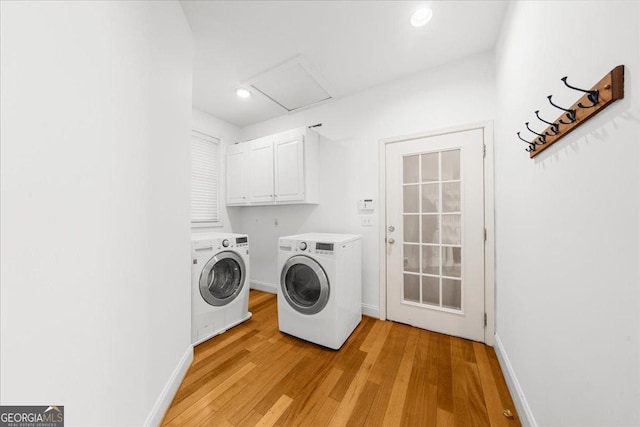 laundry room featuring light wood finished floors, baseboards, separate washer and dryer, cabinet space, and attic access