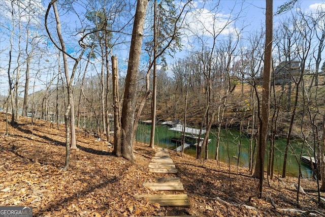 view of dock featuring a wooded view and a water view