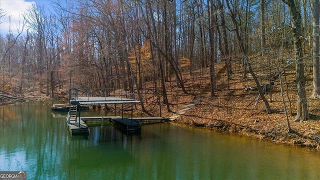 view of dock with a forest view and a water view