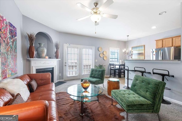 carpeted living room featuring ceiling fan with notable chandelier