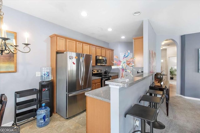 kitchen with kitchen peninsula, stainless steel appliances, light carpet, and a kitchen breakfast bar