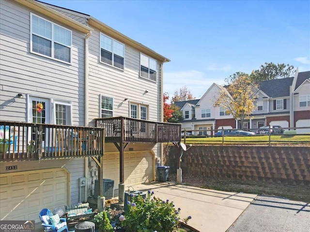 rear view of property with a garage, central AC unit, and a deck