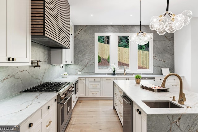 kitchen with white cabinets, hanging light fixtures, sink, appliances with stainless steel finishes, and light stone counters