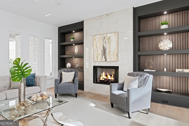 living room featuring built in shelves, a fireplace, and light wood-type flooring