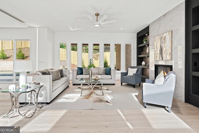 living room with ceiling fan, a healthy amount of sunlight, built in features, and a fireplace