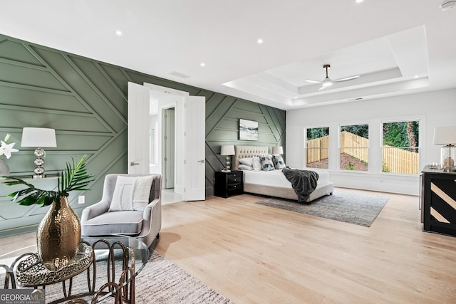 bedroom with a tray ceiling, ceiling fan, and light hardwood / wood-style floors