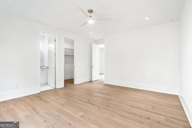 unfurnished bedroom featuring a walk in closet, light hardwood / wood-style flooring, ensuite bath, ceiling fan, and a closet