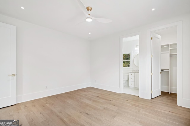 unfurnished bedroom featuring ceiling fan, a spacious closet, connected bathroom, light hardwood / wood-style floors, and a closet