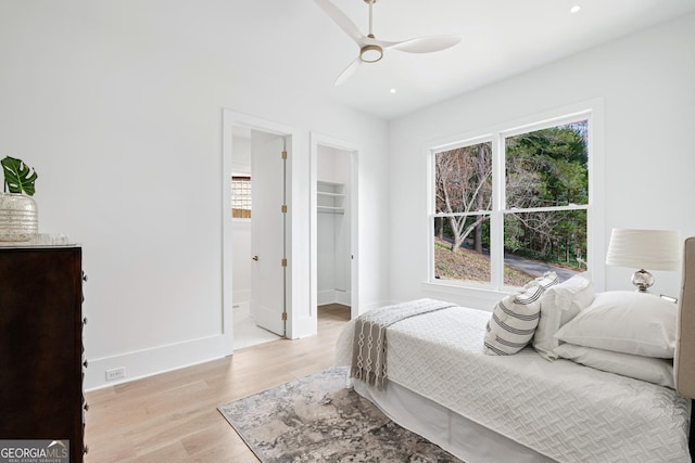 bedroom featuring ensuite bath, ceiling fan, multiple windows, and light wood-type flooring