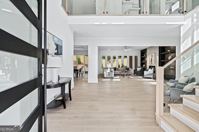 foyer entrance featuring ceiling fan, a towering ceiling, and light wood-type flooring