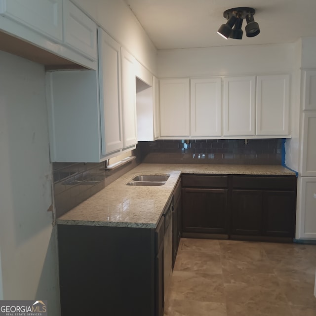 kitchen with white cabinetry, light stone counters, sink, and tasteful backsplash