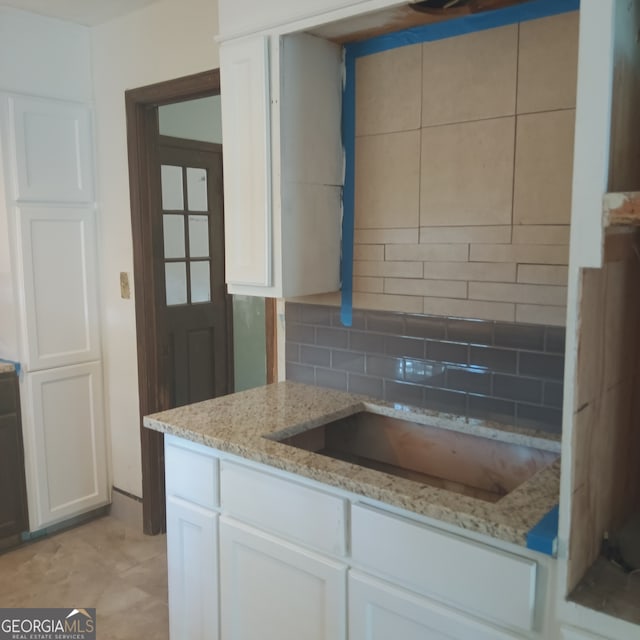 kitchen featuring white cabinetry, decorative backsplash, and light stone counters