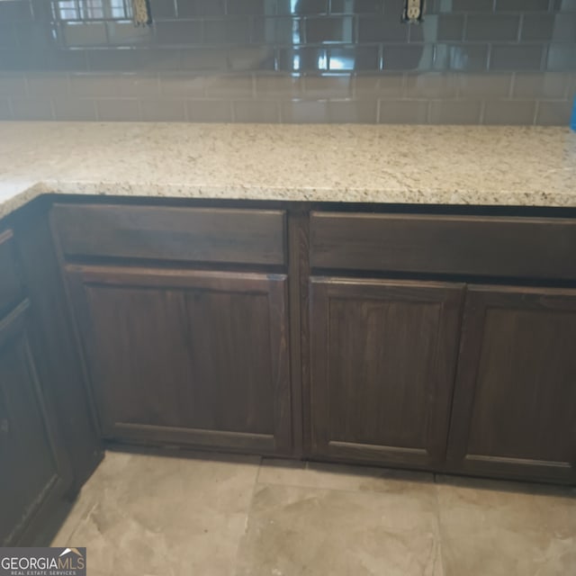 room details with dark brown cabinets, decorative backsplash, and light stone counters