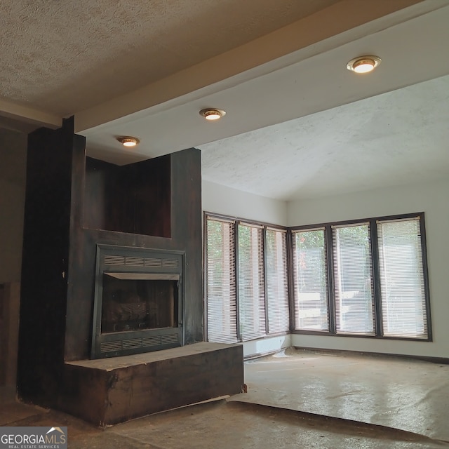 unfurnished living room featuring a large fireplace and a textured ceiling