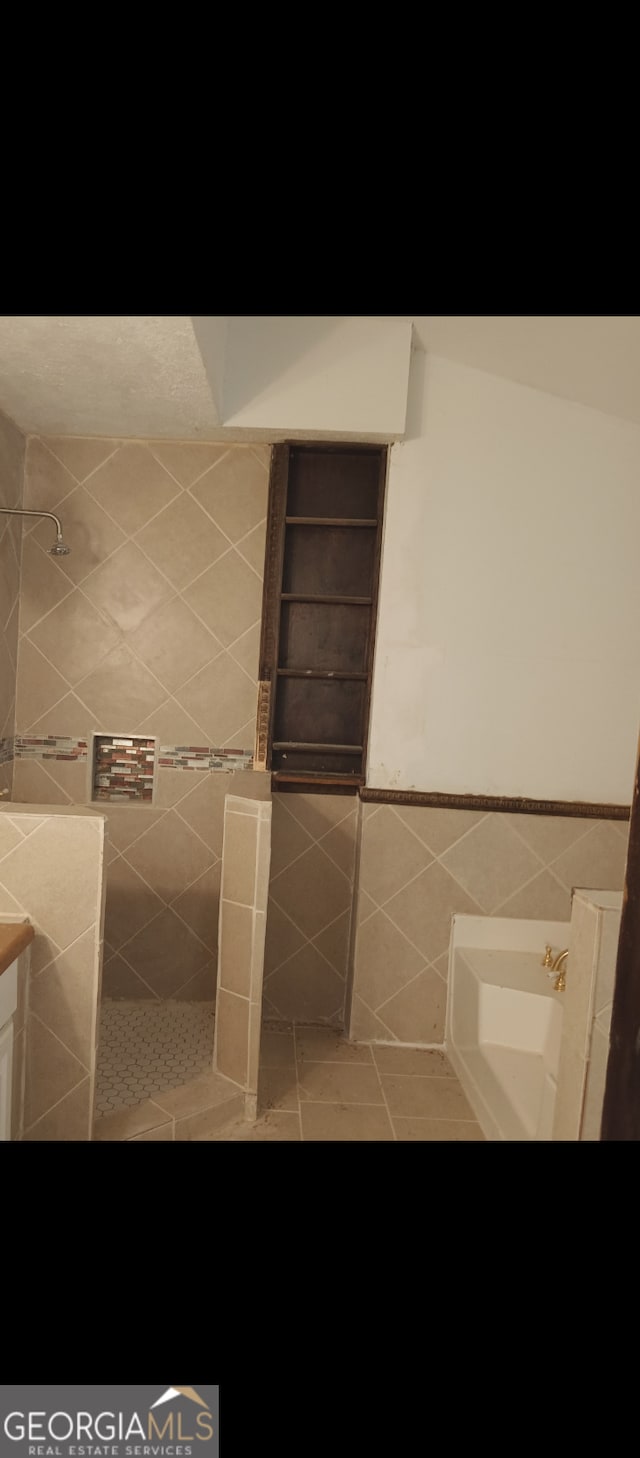 bathroom featuring vanity, tile walls, tile patterned flooring, and tiled shower