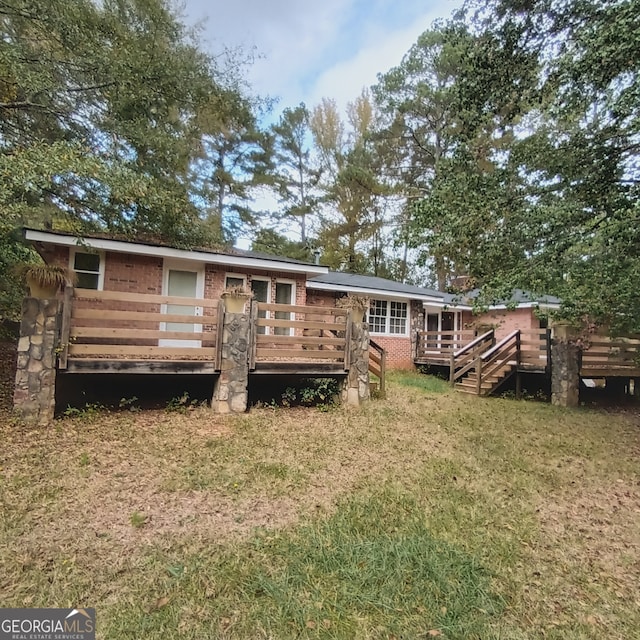 back of house featuring a lawn and a deck