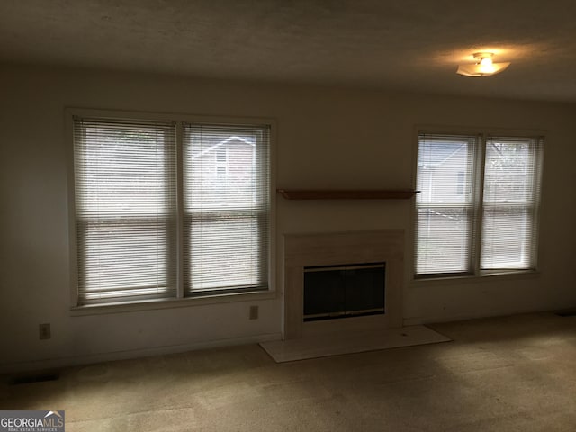 unfurnished living room featuring light colored carpet and plenty of natural light