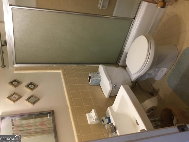 bathroom with toilet, combined bath / shower with glass door, and backsplash