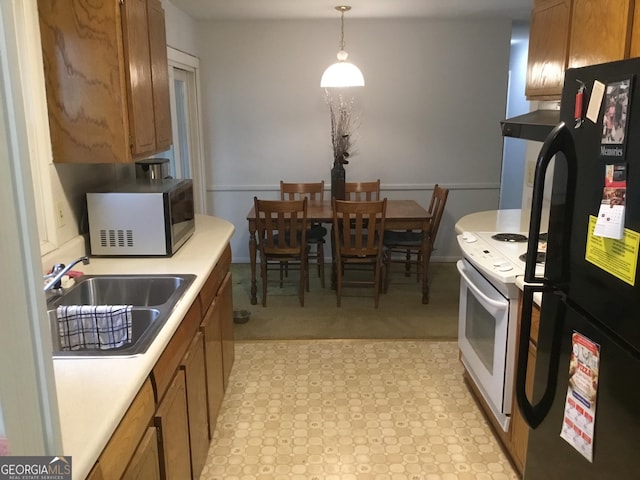 kitchen featuring sink, black fridge, decorative light fixtures, electric stove, and exhaust hood