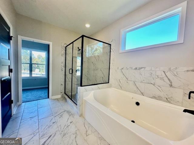 full bathroom with healthy amount of natural light, a garden tub, a stall shower, and baseboards