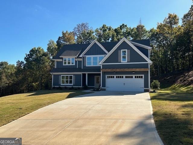 craftsman inspired home featuring concrete driveway, an attached garage, and a front yard