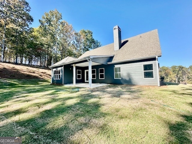 back of property with a patio area and a lawn